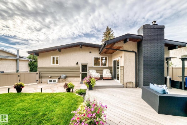 Backyard with a large wooden deck, outdoor seating, and a black brick chimney. - 15011 55 St Nw, Edmonton