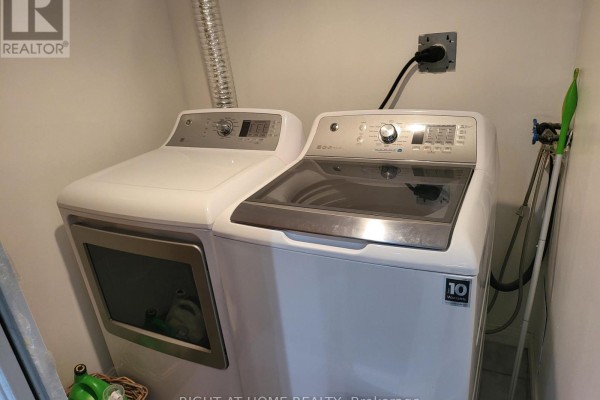 White GE washer and dryer units in a small room. - 1502 - 88 Corporate Drive, Toronto