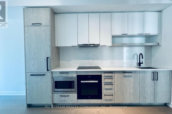 A modern kitchen with light wood cabinets, white countertops, and stainless steel appliances. - 1502 - 91 Montclair Avenue, Toronto