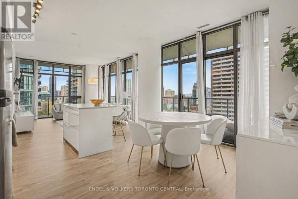 Open concept living and dining area with a white island, round table, and floor-to-ceiling windows. - 1503 - 33 Charles Street E, Toronto