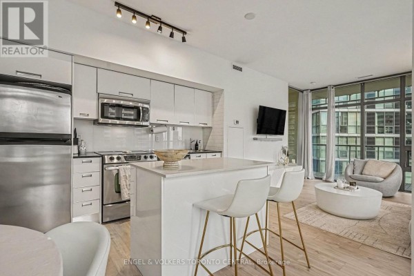 Modern kitchen with white cabinetry, stainless steel appliances, and a central island with bar stools. - 1503 - 33 Charles Street E, Toronto