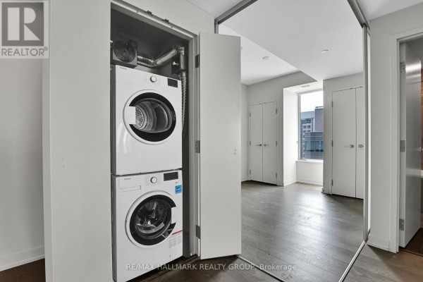 Open concept kitchen and living area with white cabinets, island, hardwood floors, and city view. - 1504 - 101 Queen Street, Ottawa