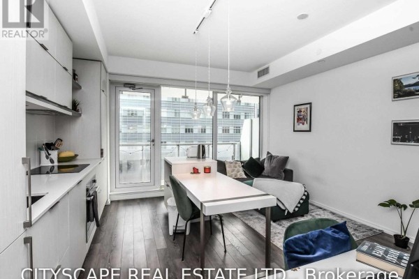 Open-concept kitchen and living area with white cabinets, dark wood floors, and a city view from the balcony. - 1504 - 197 Yonge Street, Toronto