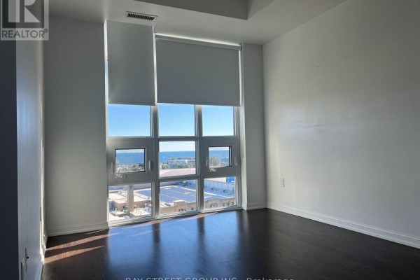 Bedroom with dark wood floor and large window offering a view of Exhibition Place and Lake Ontario. - 1504 - 65 East Liberty Street, Toronto