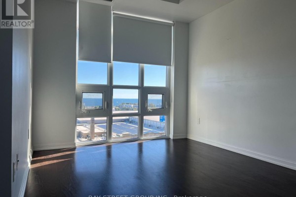 Another view of the bedroom with dark wood floors and a large window facing Exhibition Place and Lake Ontario. - 1504 - 65 East Liberty Street, Toronto