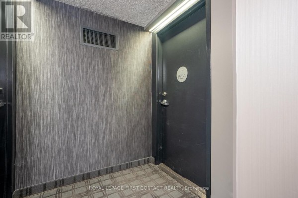 Hallway outside apartment 1504 with textured wallpaper and dark door. - 1504 - 75 Ellen Street, Barrie