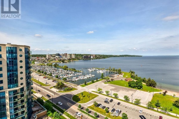 View from apartment balcony of a city skyline, marina, and large lake under a blue sky. - 1505 - 37 Ellen Street, Barrie