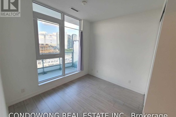 Bright bedroom with a large window, balcony access, and light wood floors. - 1505 - 950 Portage Parkway, Vaughan