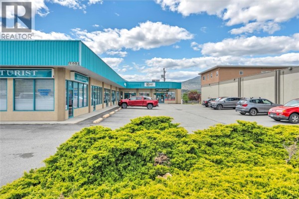 Exterior of a commercial building with teal overhang and multiple storefronts, including a dentist's office. - 1505 Main Street, Penticton