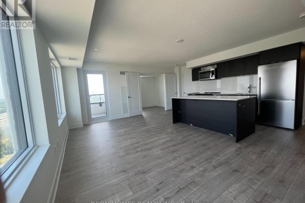 Open concept living area with light wood floors, a dark kitchen island, and stainless steel appliances. - 1506 - 10 Eva Road, Toronto