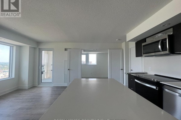 Interior view showing a modern kitchen with a large island and dark cabinets, connected to a living space. - 1506 - 10 Eva Road, Toronto