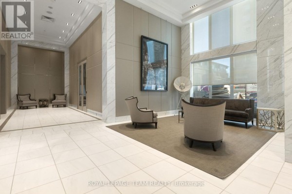Lobby seating area with two chairs, a sofa, coffee table, and artwork in a marble-clad hallway. - 1506 - 111 Champagne Avenue S, Ottawa