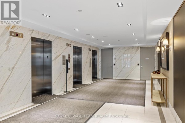 Elevator lobby with four stainless steel elevator doors, marble walls, and a console table. - 1506 - 111 Champagne Avenue S, Ottawa