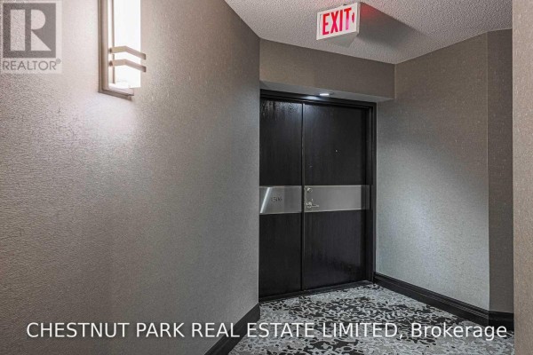 Hallway with textured grey wallpaper, a modern wall sconce, and a double dark wood apartment door with number 1506. - 1506 - 131 Beecroft Road, Toronto