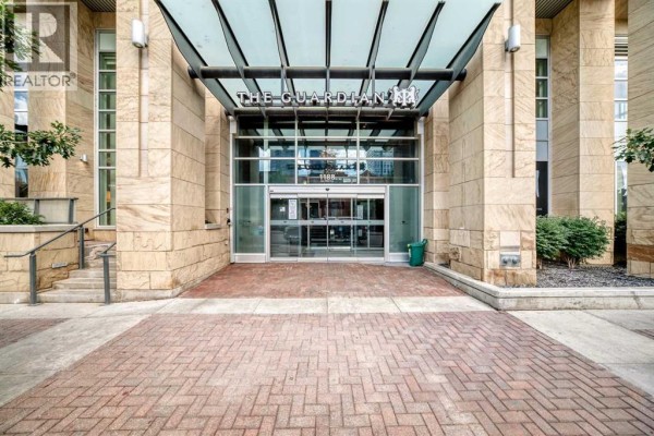 Glass and stone entrance to The Guardian building with a red brick walkway. - 1507, 1188 3 Street Se, Calgary