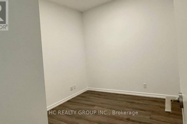 Empty room with white walls, wood-look flooring, and baseboards, seen from a doorway. - 1507 - 1000 Portage Parkway, Vaughan