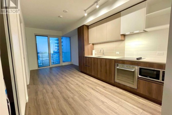 Kitchen and living area in a modern apartment with light wood cabinets, stainless steel appliances, and a balcony view. - 1507 - 1000 Portage Parkway, Vaughan