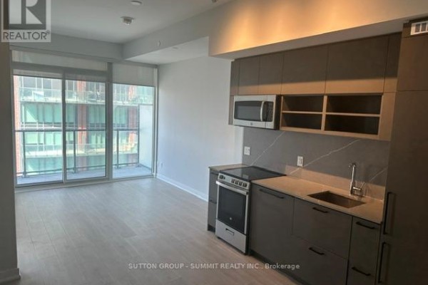Apartment living area with a balcony and a compact kitchen. - 1507 - 135 East Liberty Street, Toronto