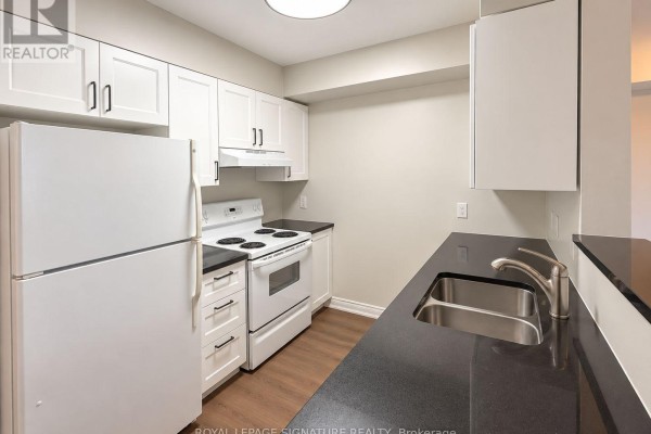 Kitchen with white cabinets, dark countertops, stainless steel double sink, and white appliances. - 1507 - 20 Olive Avenue, Toronto