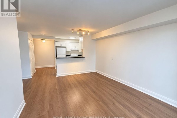Living area with light wood floors, white walls, and a view of the open kitchen. - 1507 - 20 Olive Avenue, Toronto
