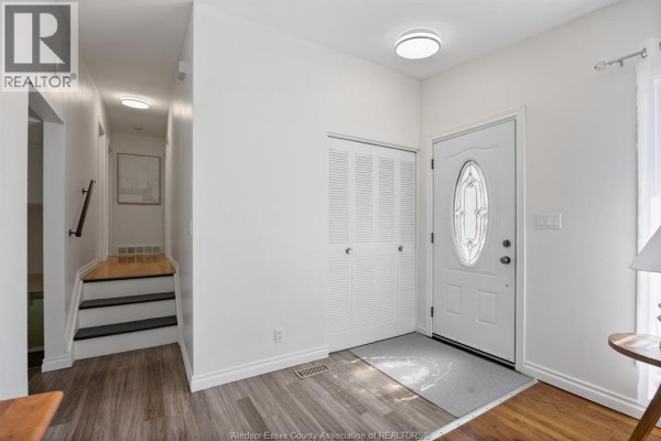 Living room with a large window, gray sofa, wooden coffee table, and hardwood floors. - 1507 St. Gabriel, Windsor