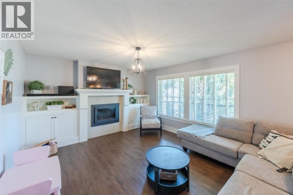 Living room with a fireplace, built-in shelves, and a sectional sofa. - 1507 Wharf Street, Summerland