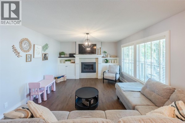 Living room with white fireplace, entertainment unit, and large windows. - 1507 Wharf Street, Summerland
