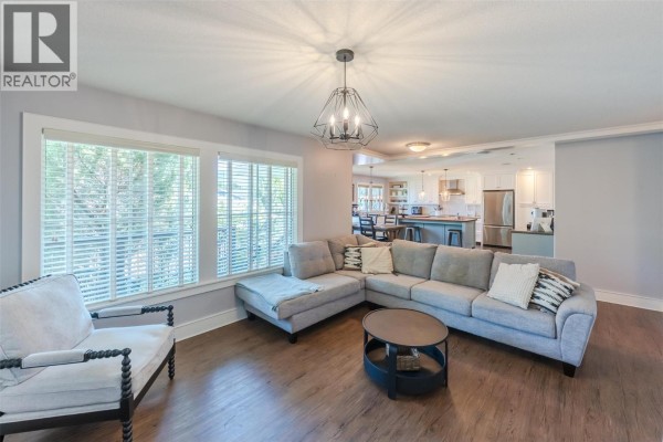 Grey sectional sofa and armchair in a living room with open view to kitchen. - 1507 Wharf Street, Summerland