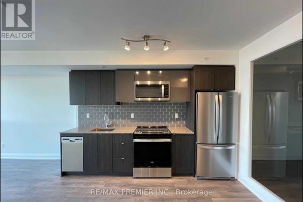 Compact kitchen with dark grey cabinets, stainless steel appliances, and grey subway tile backsplash. - 1508 - 1461 Lawrence Avenue W, Toronto