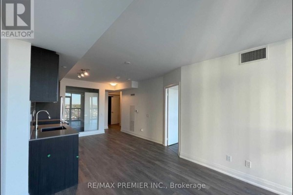 View of the living area, kitchen, and hallway with a door leading to another room. - 1508 - 1461 Lawrence Avenue W, Toronto