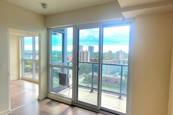 Living room with large windows, sliding glass door to balcony, and view of apartment buildings. - 1508 - 2 Sonic Way, Toronto