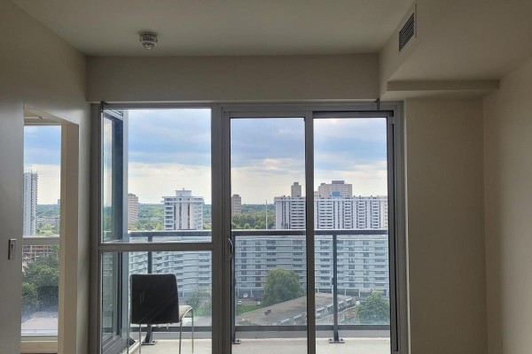 View from an apartment balcony with sliding glass doors, overlooking surrounding city buildings. - 1508 - 2 Sonic Way, Toronto