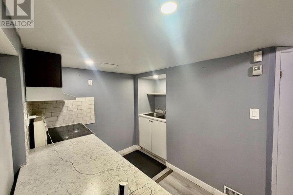 Close-up of a stovetop and subway tile backsplash in a small kitchenette with grey walls. - 1508 Major Oaks Road, Pickering