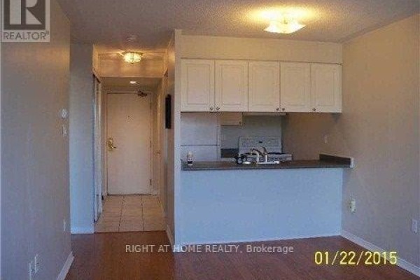 An open concept living area showing a kitchen with white cabinets and a dining nook. - 1509 - 887 Bay Street, Toronto
