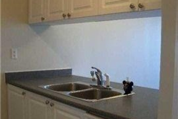 Close-up of a double sink and faucet in a kitchen with dark grey countertops. - 1509 - 887 Bay Street, Toronto