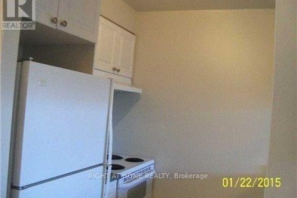 A white refrigerator and electric stove in a compact kitchen with white cabinets. - 1509 - 887 Bay Street, Toronto