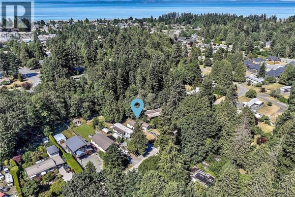 Aerial view of a residential area surrounded by dense evergreen trees, with a blue marker indicating a property. - 1509 Mason Trail, Parksville