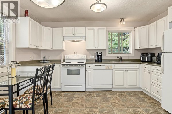White kitchen cabinets with a white oven, dishwasher, refrigerator, and a glass-top dining table with chairs. - 1509 Mason Trail, Parksville
