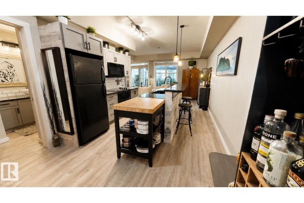 Kitchen with grey cabinets, black appliances, and a butcher block island with bar stools. - #151 4827 104a St Nw Nw, Edmonton