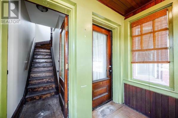 View of a staircase and an interior doorway from a sunroom with green trim. - 151 Albert St E, Sault Ste  Marie