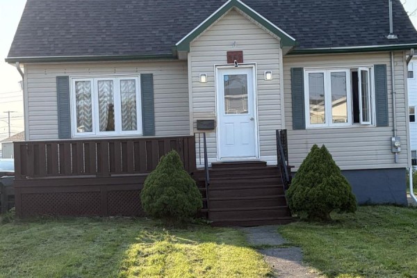 Close-up of the cream-colored house entrance with a white door, flanked by windows with green shutters. - 151 Gray Street, Sydney