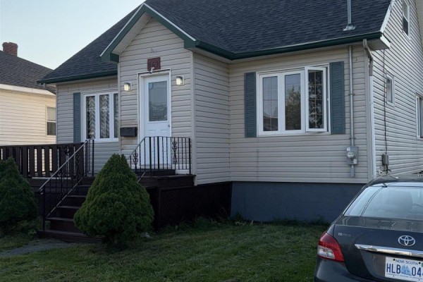 Right side view of the cream-colored house with a dark brown deck and stairs, and a car parked in the driveway. - 151 Gray Street, Sydney