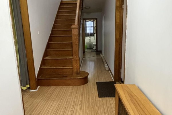 Interior hallway with light wood laminate flooring, a wooden staircase, and a doorway leading to a bathroom. - 151 Gray Street, Sydney