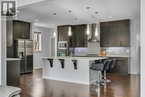 Laundry room with front-loading washer and dryer, shelving, and storage bins. - 151 Stonemere Green, Chestermere