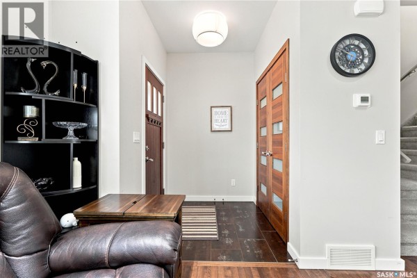 Interior hallway with dark wood doors, tiled floor, and a large shelf. - 151 Tweed Lane, Saskatoon