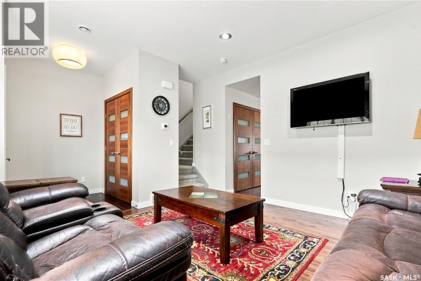 Living room with brown leather sofas, a coffee table, and a mounted television. - 151 Tweed Lane, Saskatoon