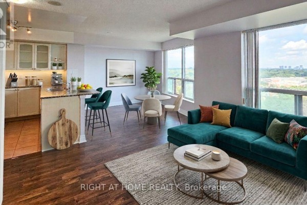 Open concept living, dining, and kitchen area with a teal sectional sofa and island. - 1510 - 188 Doris Avenue, Toronto