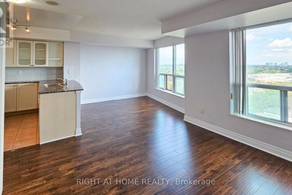 View of an open concept living area and kitchen with large windows and city views. - 1510 - 188 Doris Avenue, Toronto