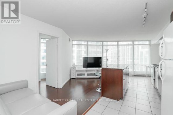 Living area with white sofa, hardwood floors, television, and large windows. - 1510 - 361 Front Street W, Toronto