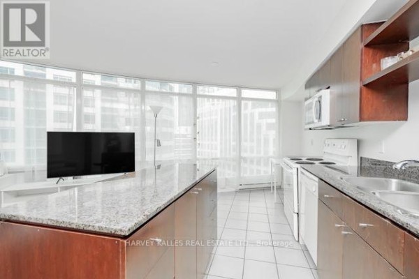 Open concept kitchen and living area with granite island and city view. - 1510 - 361 Front Street W, Toronto